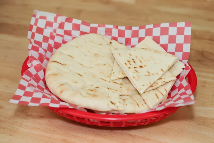 Warm pita bread and wedges in a serving basket.