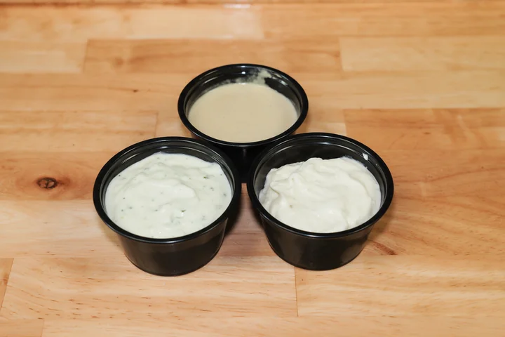 Small cups of tzatziki, tahini and garlic sauce.