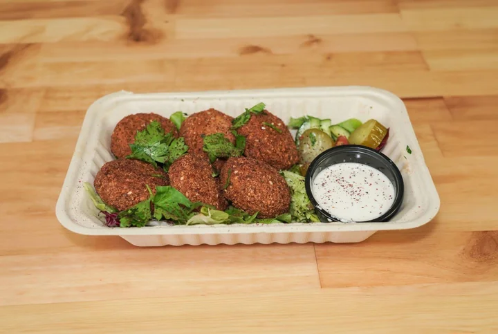 Six crispy falafel balls served with a cup of sauce.