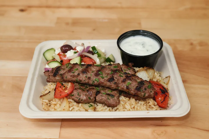 Grilled kufta kebabs over rice with Greek salad and tzatziki.